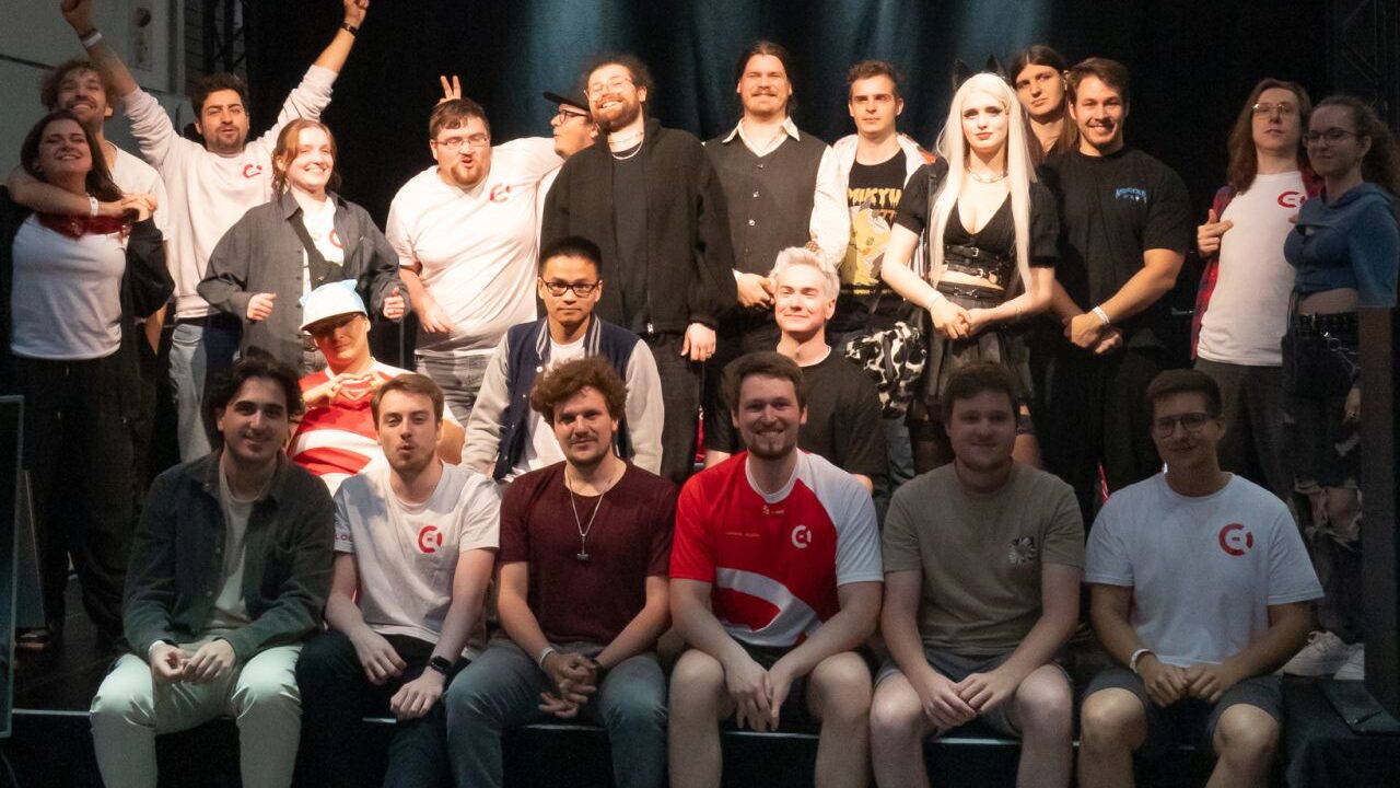 Die Helfer des eSports Cologne e.V. sitzen auf der Bühne ihres Standes auf der Dokomi 2025