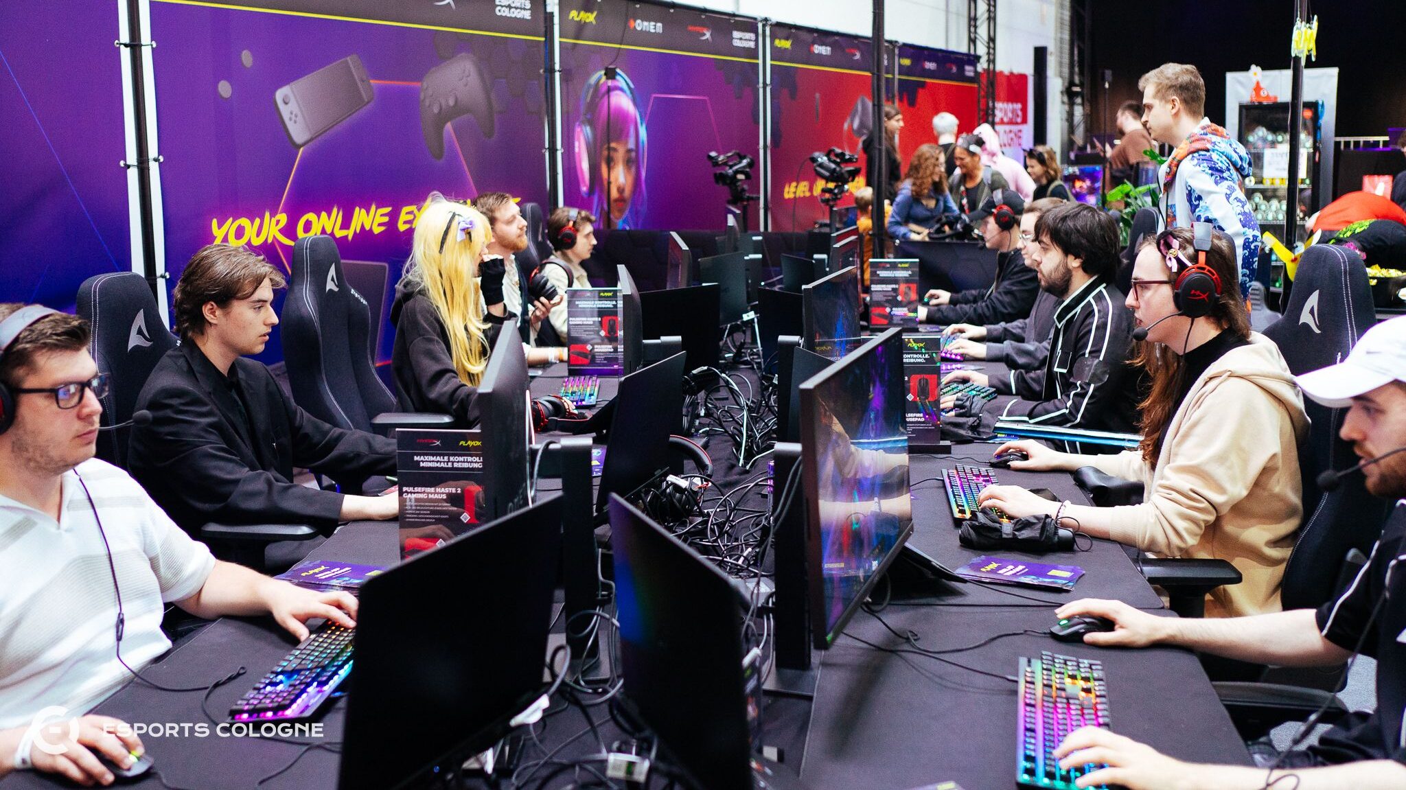 Teilnehmen spielen an den 1 gegen 1 Stationen des eSports Cologne auf deren Stand der Dokomi 2025